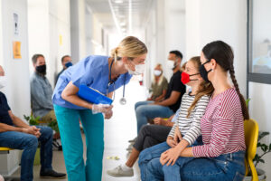 Nurse practitioner speaking with young girl and mom in waiting room